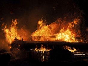 Arson or nature disaster, burning fire flame on wooden house roof