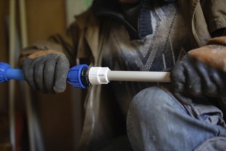 Close-up of gloved hands adjusting a pipe fitting