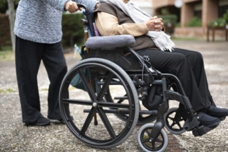 Elderly woman in wheel chair spending time with her daughter in the garden of nursing home. graphy