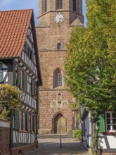View of church with clock and half-timbered houses in a small cobbled village street, Kandel,