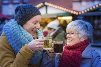 Two woman standing at the Christmas market drinking mulled wine