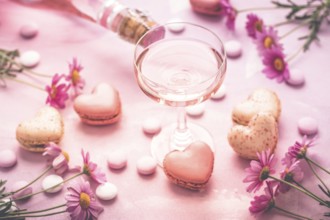 Happy Mothers Day - sweet macarons in heart shape and glass of rose sparkling wine with flowers in