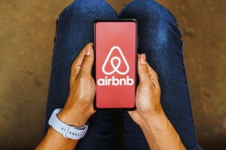 In this photo illustration, the Airbnb logo is displayed on a smartphone screen