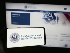 Stuttgart, Germany, 10-29-2023: Person holding smartphone with seal of agency United States Customs