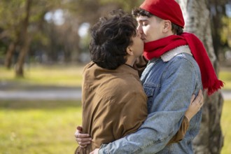 Young gay couple kissing in a park