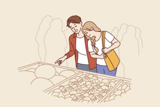 Man and woman do shopping at market and stand near crates of vegetables at farmers fair. Happy