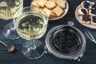 Caviar and champagne, vintage style, with bread and toasts on a dark blue wooden background