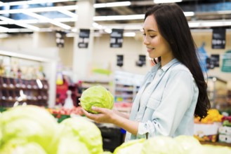 Smiling asian woman choosing cabbage market