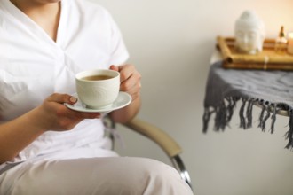 Cropped photo of happy lovely young female health worker laughing sincerely while holding cup of