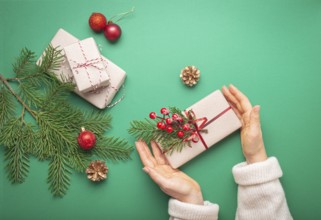 Christmas or New Year celebration green paper festive background with female hands holding wrapped