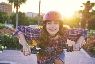 Girl portrait on bicycle with helmet smiling happy at the flowers park outdoor
