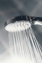 Shower head with flow of water spilling out closeup. Modern shower head splashing water close up