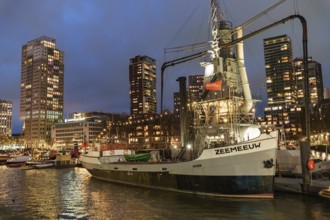 Illuminated ship in the harbour with skyscrapers in the background at night, Rotterdam, Netherlands
