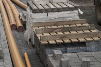 Construction materials including paving stones, orange pipes and wooden pallets laying on a