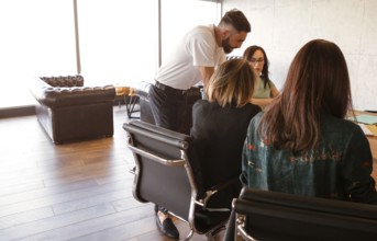 Smiling diverse colleagues gather in boardroom to discuss financial statistics together, happy