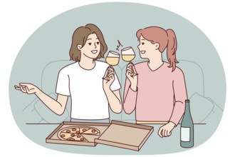 Happy young women sitting on couch at home eating pizza drinking wine. Smiling girls have fun