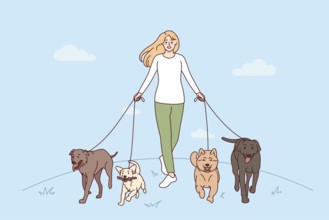 Smiling young woman with dogs on leashes walking in park. Happy girl pet walker with domestic