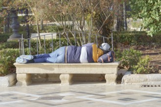 Homeless man sleeping on a park bench