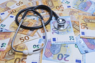 Stethoscope with euro banknotes in the background, health care costs concept