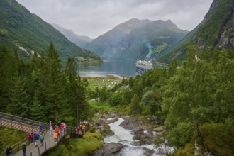 An impressive landscape with a raging waterfall, surrounded by green mountains and forests, with a