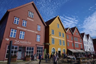 Traditional wooden houses under a blue sky with pitched roofs and multiple windows in a sunny old
