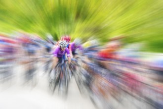 Cyclist in sportswear and helmet riding at high speed on a road, race, the motion blur emphasises
