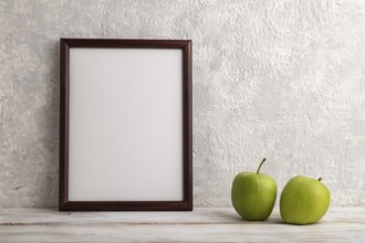 Brown wooden frame mockup with green apple on gray concrete background. Blank, vertical
