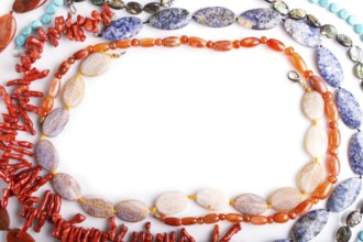 Frame of semiprecious stone beads on white background, top view