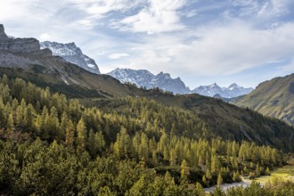 Mountain panorama with steep rocky peaks, yellow-coloured larches in autumn, hike to the summit of