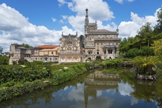 Historisches Schloss mit reflektiertem Bild im See, umgeben von Bäumen und bewölktem Himmel,