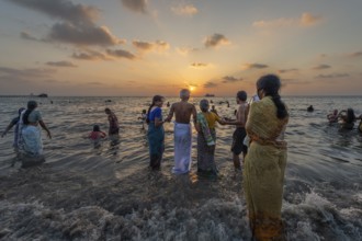 Hindu pilgrims take a holy dip in the sea at sunrise at Ghat Agni Theertham, Rameswaram or
