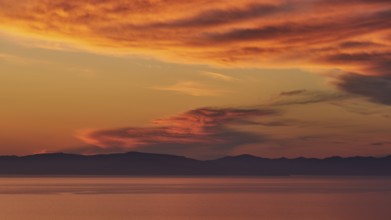 Intense twilight colours in the sky over calm sea and coastline, sunriseMani Peninsula,
