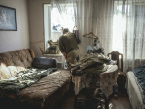 Gennady, 48 years old, stationed in Kupyansk, looking out of the window of the house where his unit