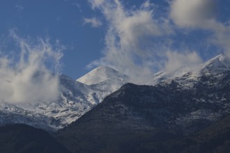 Mountain peaks with snow and clouds under a blue sky, Lefka Ori, White Mountains, mountain massif,