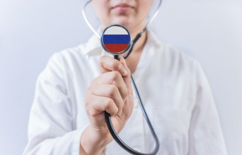 Female doctor holding stethoscope with with Russia flag. Russia health and care concept