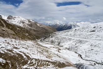 Winterliche Landschaft in den schneebedeckten Bergen von Andorra mit einer Straße und Wolken am