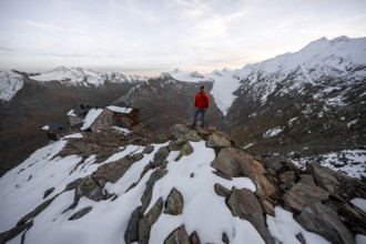 Mountaineer looking at mountain panorama and glacier, mountain hut Ramolhaus in autumn with snow,