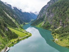 An idyllic mountain lake, surrounded by mountains and lush greenery, under a cloudy sky,