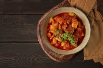 Stew with potatoes, in tomato sauce, with spices and herbs, close-up, no people, on a black