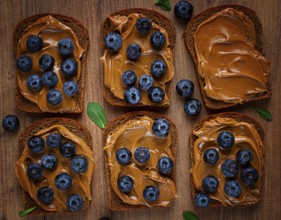 Rye bread with peanut paste and fresh blueberries, top view, no people