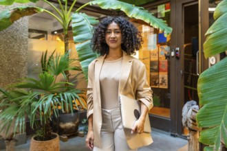 Three quarter length portrait of a beauty young businesswoman standing carrying a laptop next to