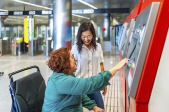 Disabled woman with wheelchair and chinese caregiver purchasing the ticket for the underground