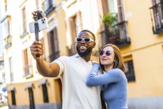 Modern multi-ethnic couple influencer recording a video vlog with smartphone in the city for online