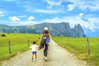 Mother and son enjoying a summer hike in the picturesque landscape of alpe di siusi, with the