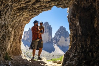 Father holding son admiring tre cime di lavaredo from inside a Tre Cime Cave during a trekking tour