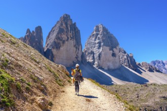 Tourists walking on a mountain path near tre cime di lavaredo, dolomites, a famous landmark in