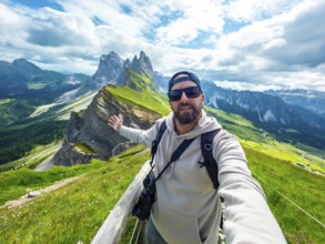 Photographer taking a selfie with outstretched arm, capturing the breathtaking seceda peaks and