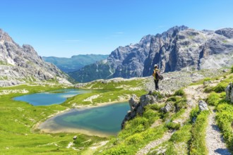 Hiker enjoying the breathtaking view of the tre cime di lavaredo peaks and the turquoise alpine