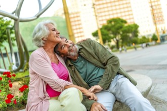 Mature couple sitting together in an urban bench contemplating the city views from the square