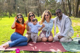 Cheerful multi ethnic friends enjoying a fun picnic in the park, laughing and bonding together with